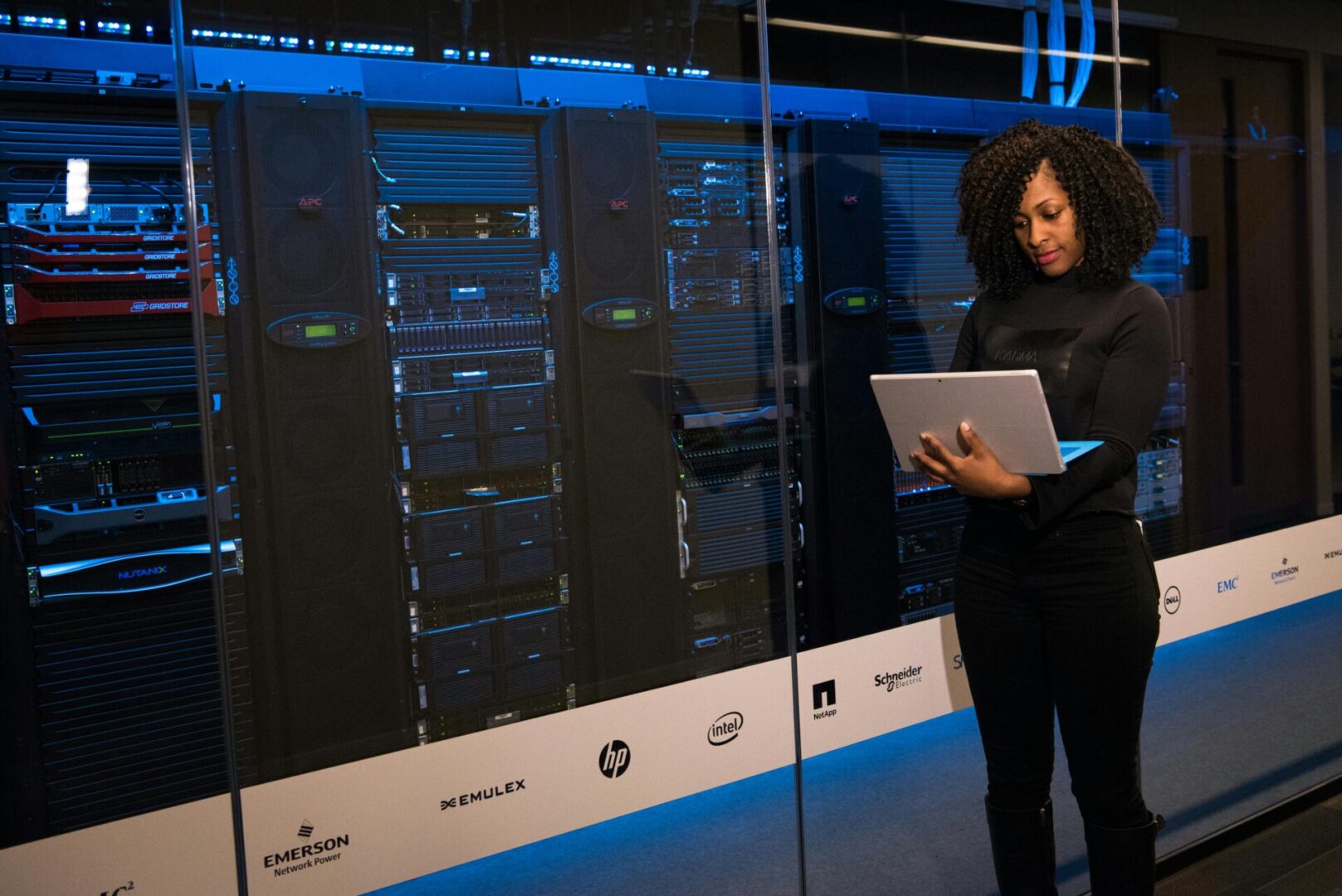 pexels-divinetechygirl-1181354 Woman working on laptop in server room.