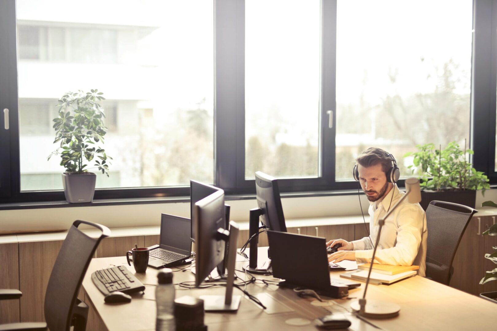 pexels-olly-845451 Man working at desk with headset.